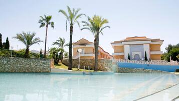 A swimming pool with a stone wall and palm trees.