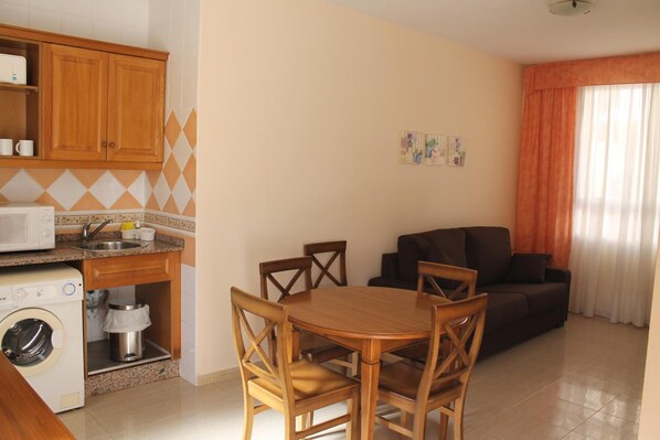 Un espacio habitable compacto con cocina, comedor y sofá.