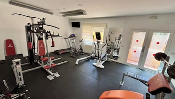Una palestra con diverse attrezzature per l'allenamento, tra cui tapis roulant, cyclette e macchinari per pesi.