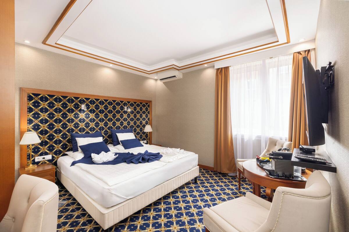 Een hotelkamer met een groot bed, een bureau met een computer, een televisie en een stoel.