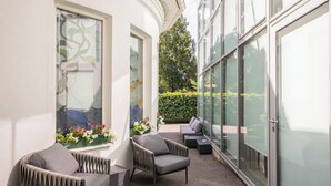Un área de estar al aire libre moderna con pared de vidrio, un sofá y una silla.