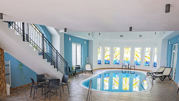 Una piscina interior con suelo de baldosas y una escalera que sube a un nivel superior.