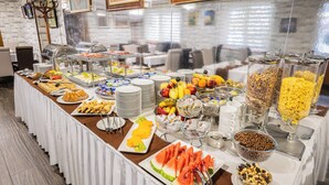Un bufé con diversos alimentos, entre ellos frutas, verduras y cereales, dispuesto sobre una mesa larga con mantel blanco.