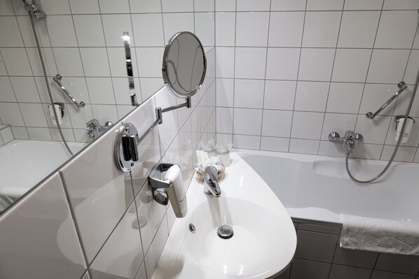 A modern bathroom with a white sink, a mirror, and a handheld showerhead.