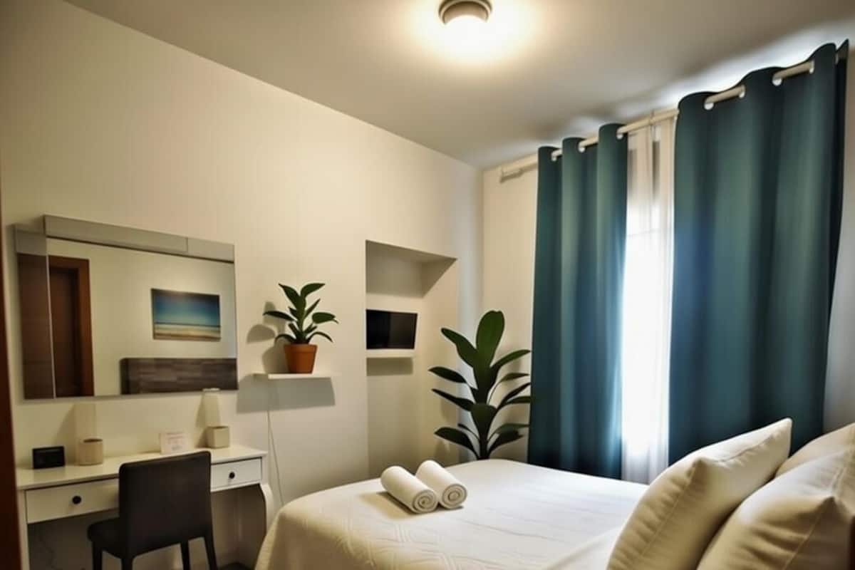 Une chambre d’hôtel moderne équipée d’un lit, d’un bureau, d’une chaise et d’une grande fenêtre avec des rideaux.