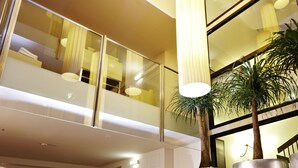 Een moderne hotel lobby met een hoge plafond, grote ramen, en een zithoek met banken en een salontafel.