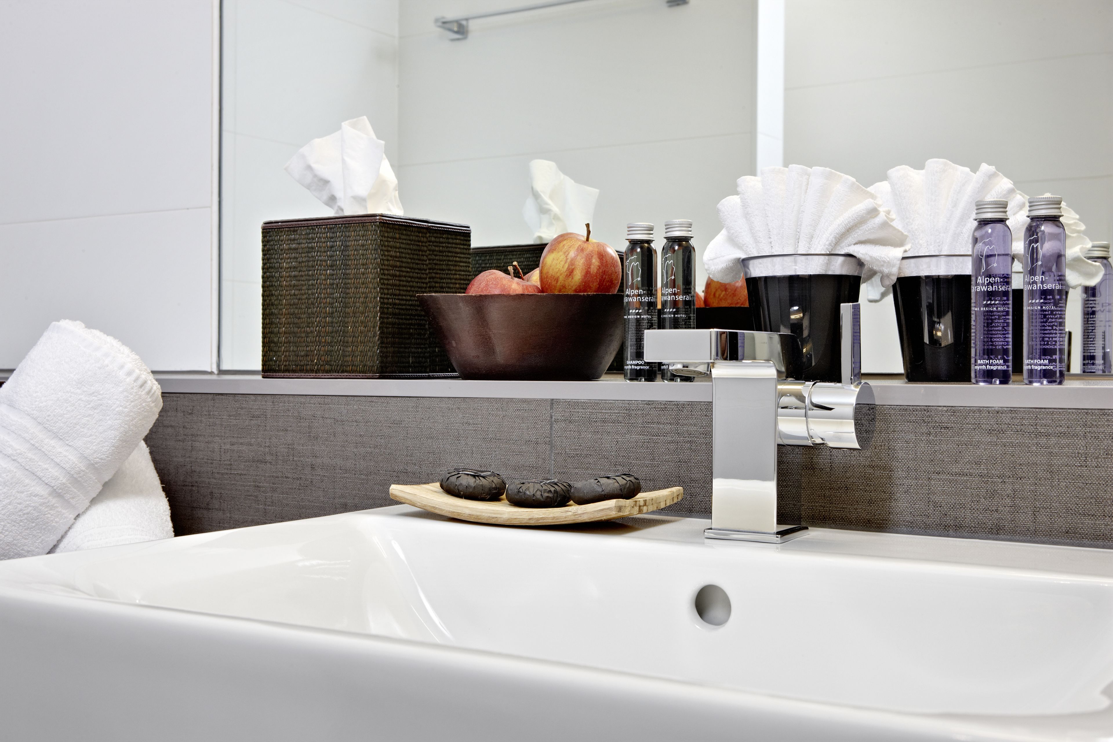 Ein modernes Badezimmer mit einer Badewanne, einer Schale Äpfel und Pflegeprodukten auf der Ablagefläche.
