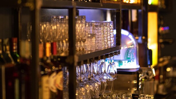 Una zona de bar con estantes llenos de botellas de licor y vasos.