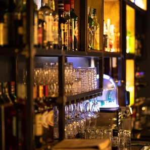 Una zona de bar con estantes llenos de botellas de licor y vasos.