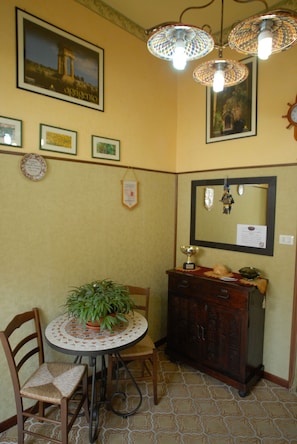 A dining area with a round table, chairs, a potted plant, a cabinet, and wall-mounted decorations. - Il Mandorlo (Agrigento)