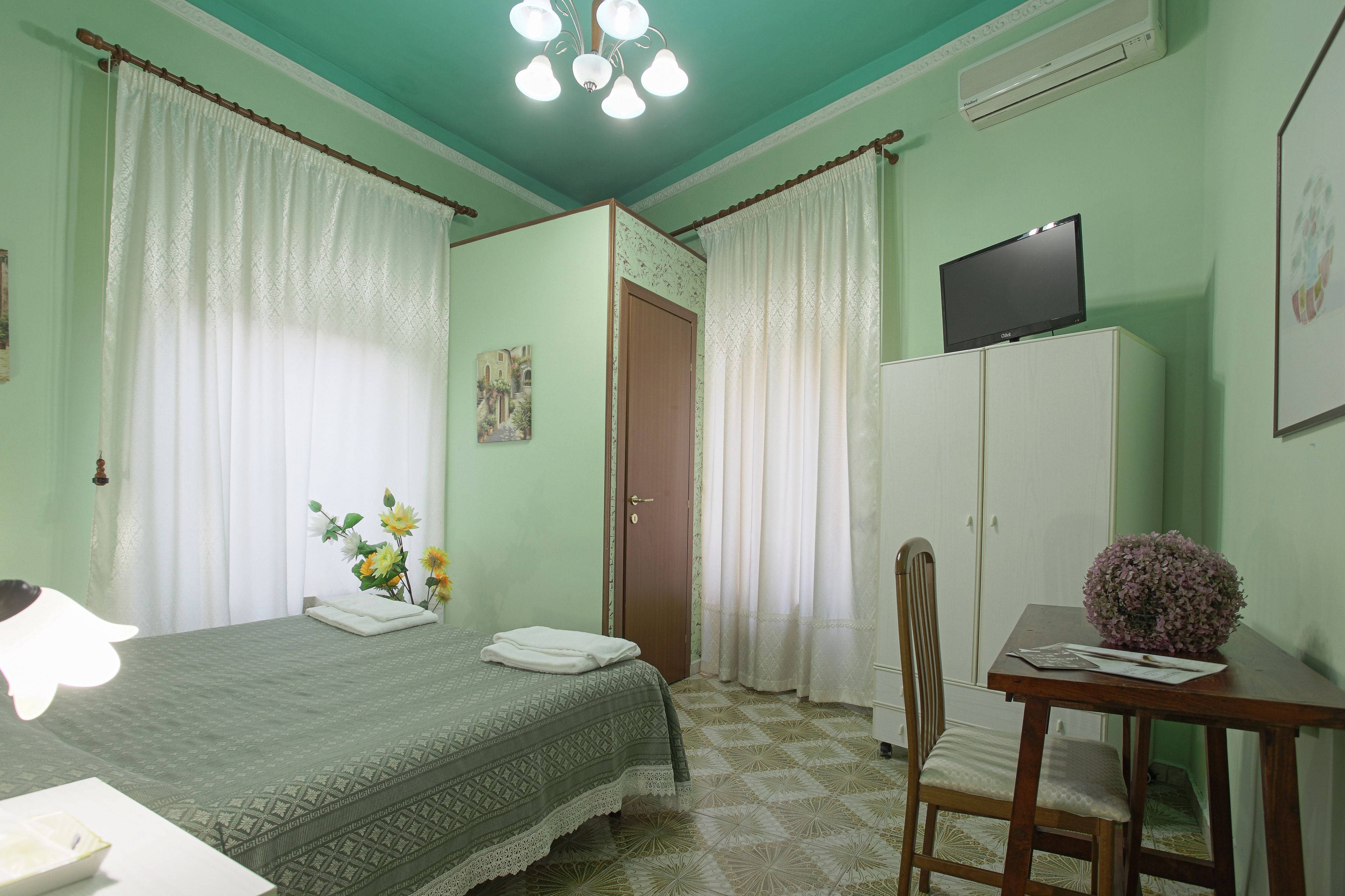 A room with a bed, a desk, a chair, a television, and a wardrobe.