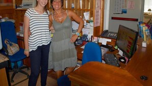Two people standing in an office with a desk, computer, and various office supplies. - Mimosa (Lignano Sabbiadoro)