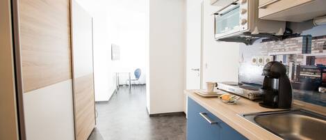 Eine moderne Küche mit Mikrowelle, Kaffeemaschine und einer Essecke mit Stuhl und Tisch.