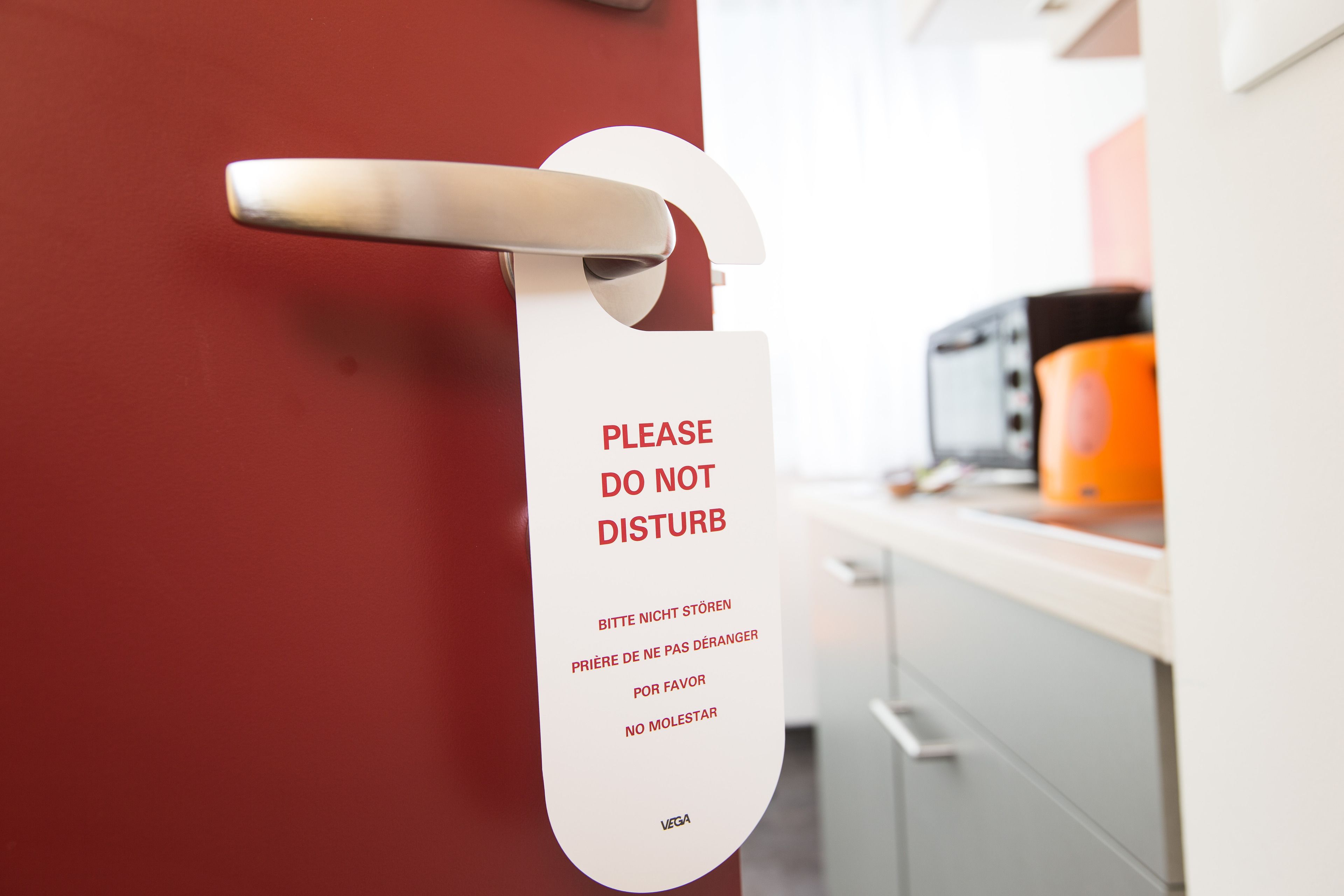 Eine Tür mit einem Schild, auf dem „Bitte nicht stören“ in verschiedenen Sprachen steht.