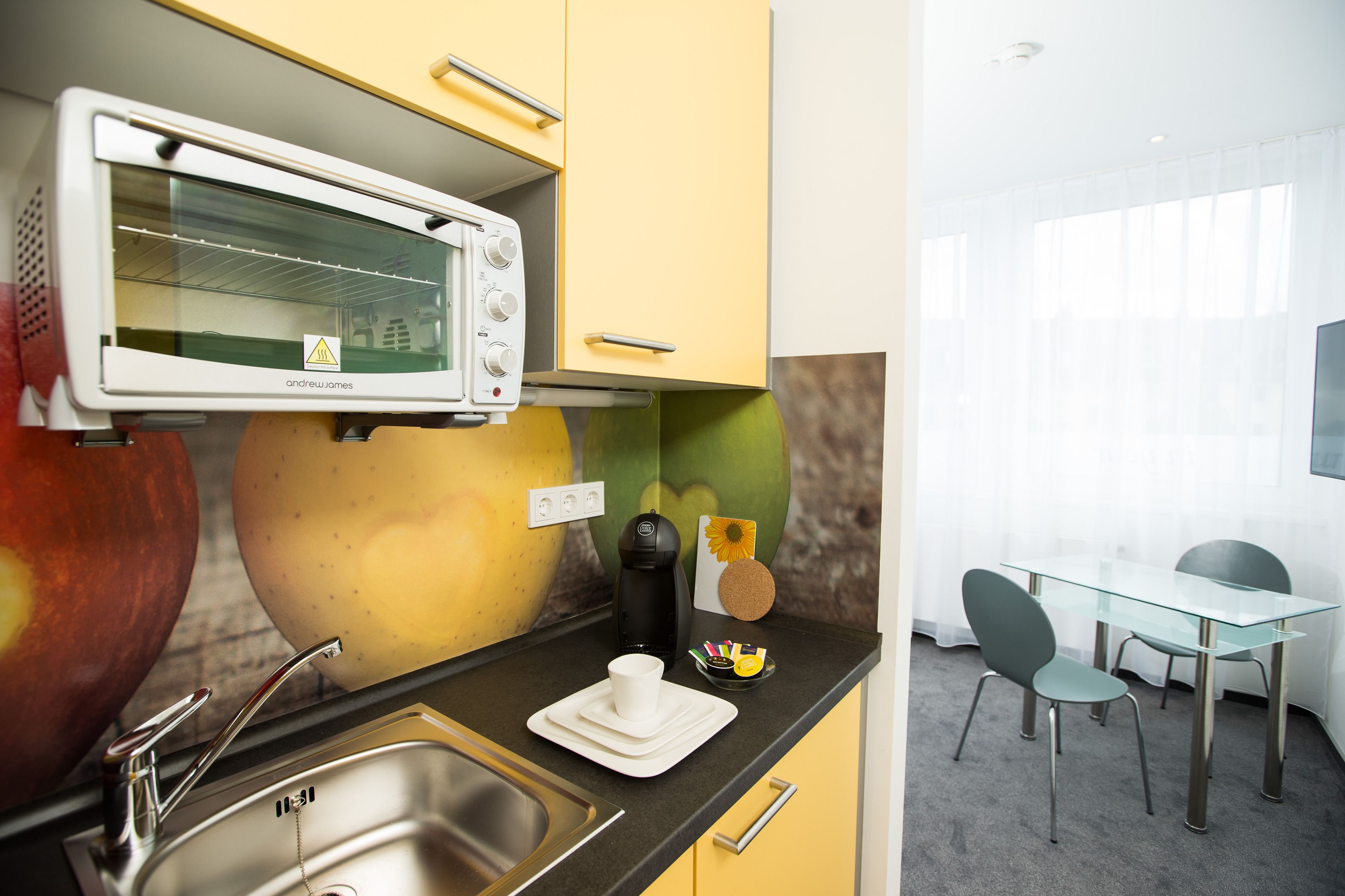 Une cuisine compacte équipée d’un four à micro-ondes, d’un évier et d’un petit coin repas avec des chaises et une table.
