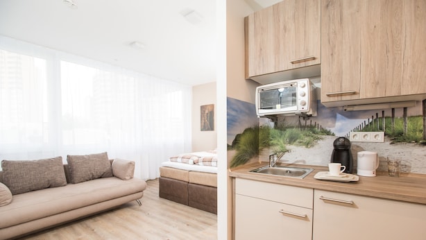 A modern kitchen with wooden cabinets, a built-in microwave, and a sink. - Design Sleepy Cologne (Cologne)