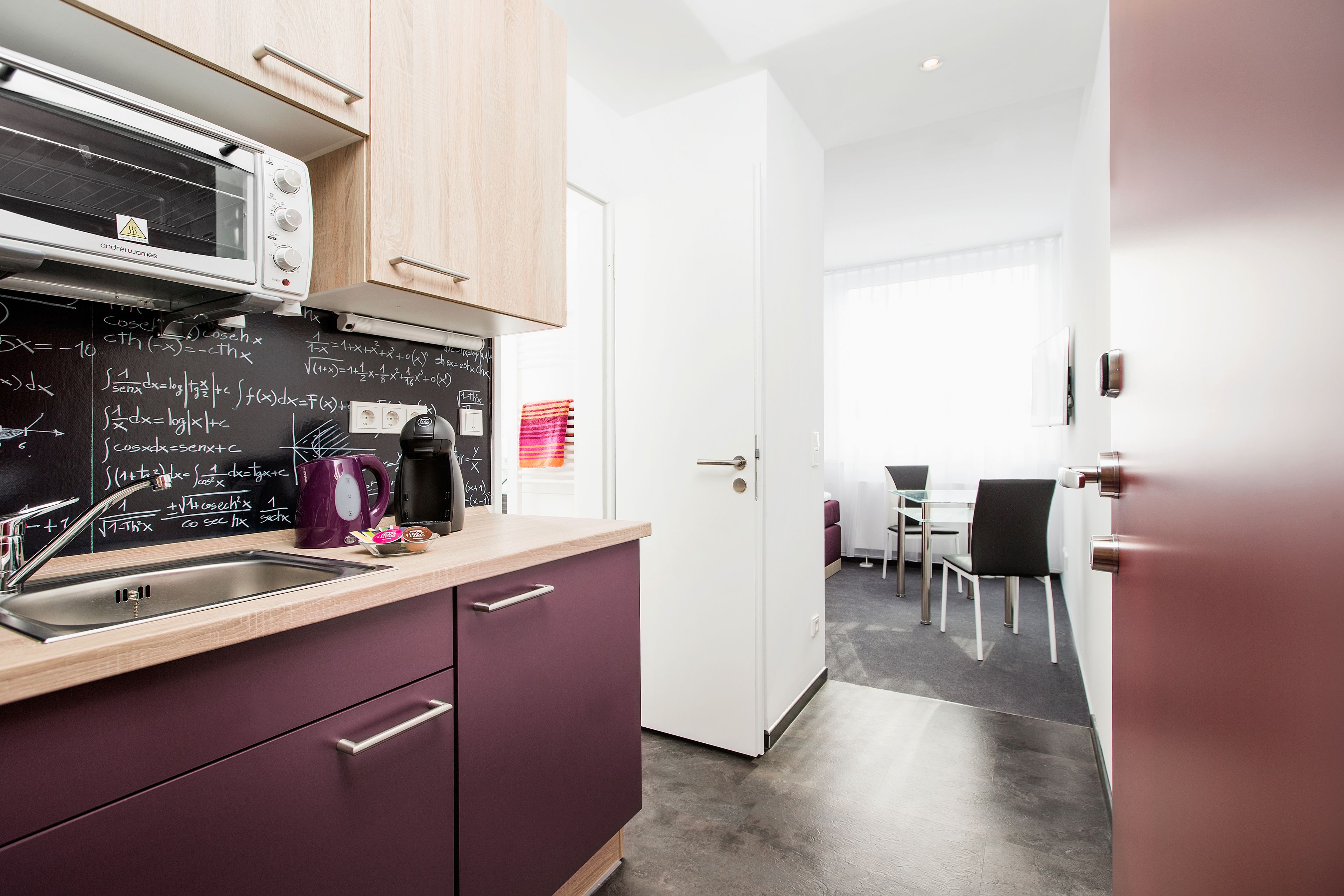A modern kitchen with a built-in microwave, a sink, and a chalkboard with mathematical equations.