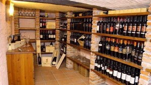 A wine cellar with shelves of wine bottles, wooden cabinets, and wine glasses. - Tenuta Luogomarchese (Pollina)