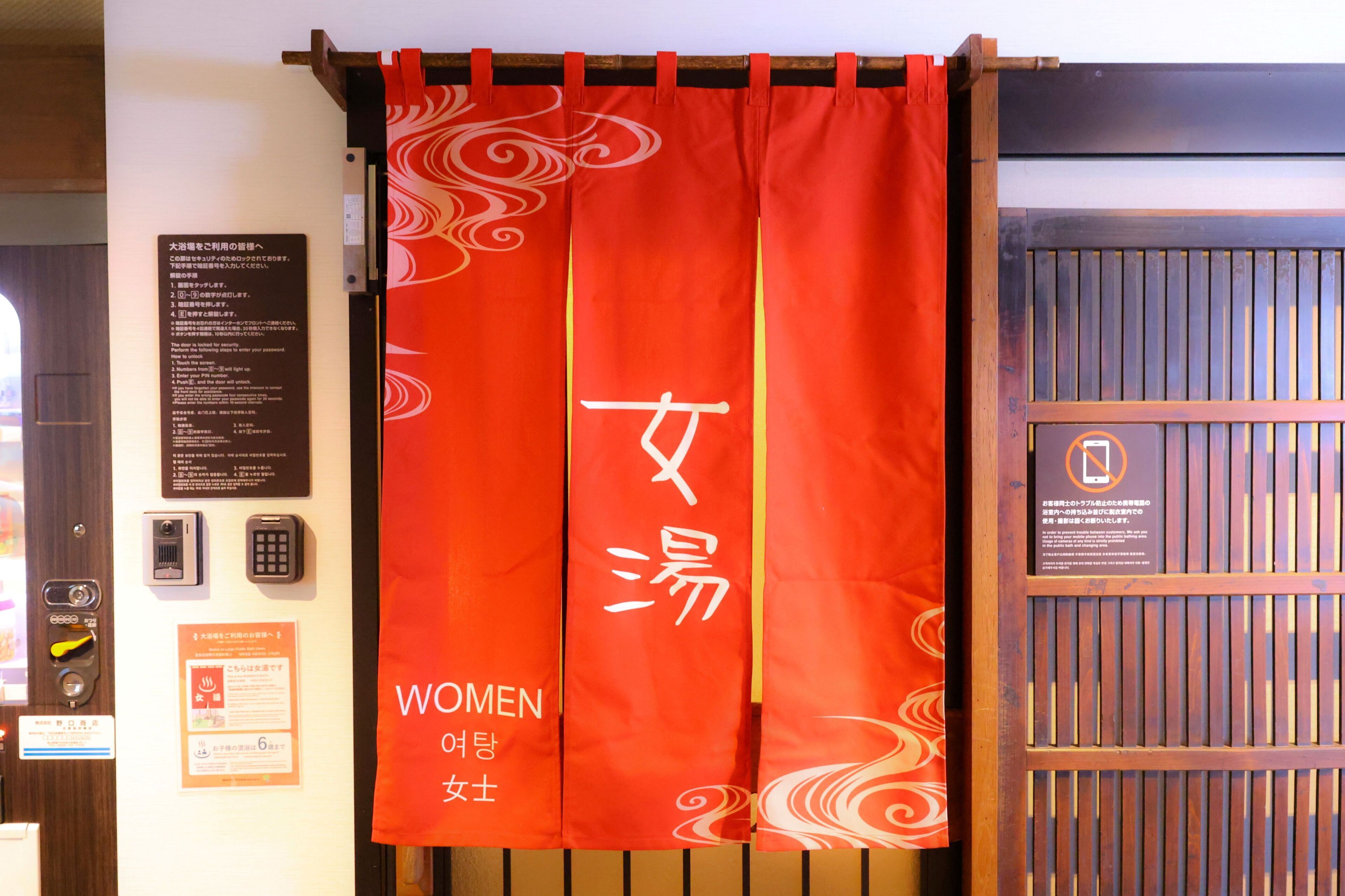 A red curtain with white text and a wooden door with a vertical panel design.