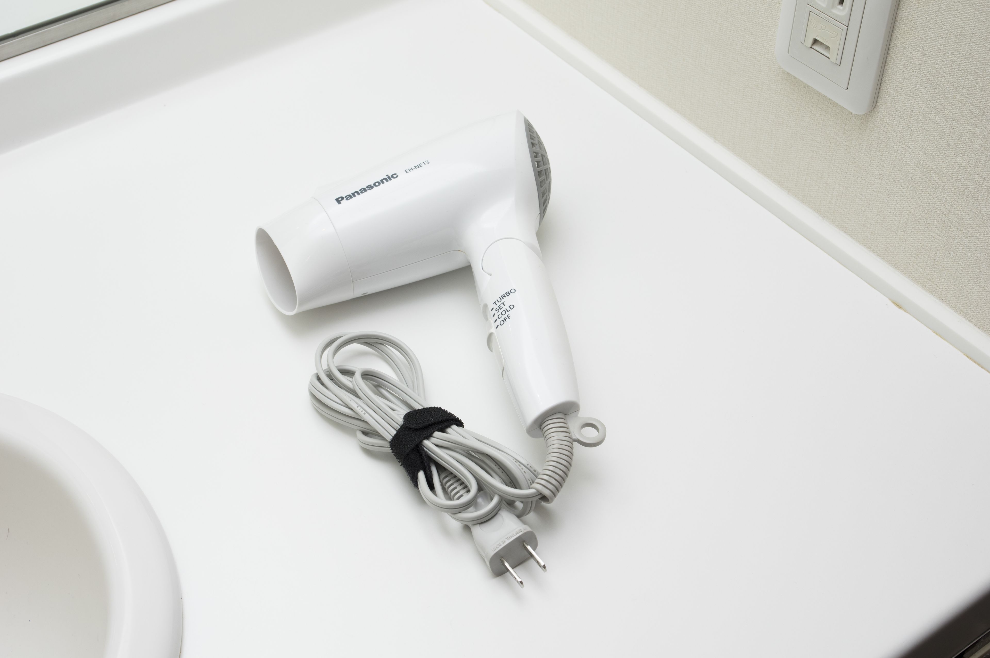 Ein Panasonic-Haartrockner mit Kabel auf einer weißen Arbeitsplatte.