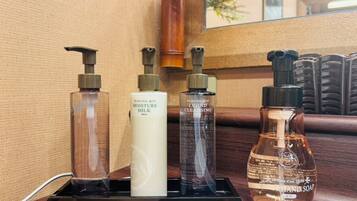 A set of toiletries including a bottle of liquid cleansing, a bottle of milk, and a bottle of hand soap, all placed on a black stand with the brand name 'POLA' visible.