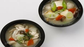 Two bowls of soup with various ingredients.