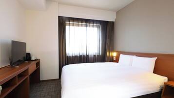 Una habitación de hotel con una cama grande, un escritorio con computadora y una ventana con cortinas.