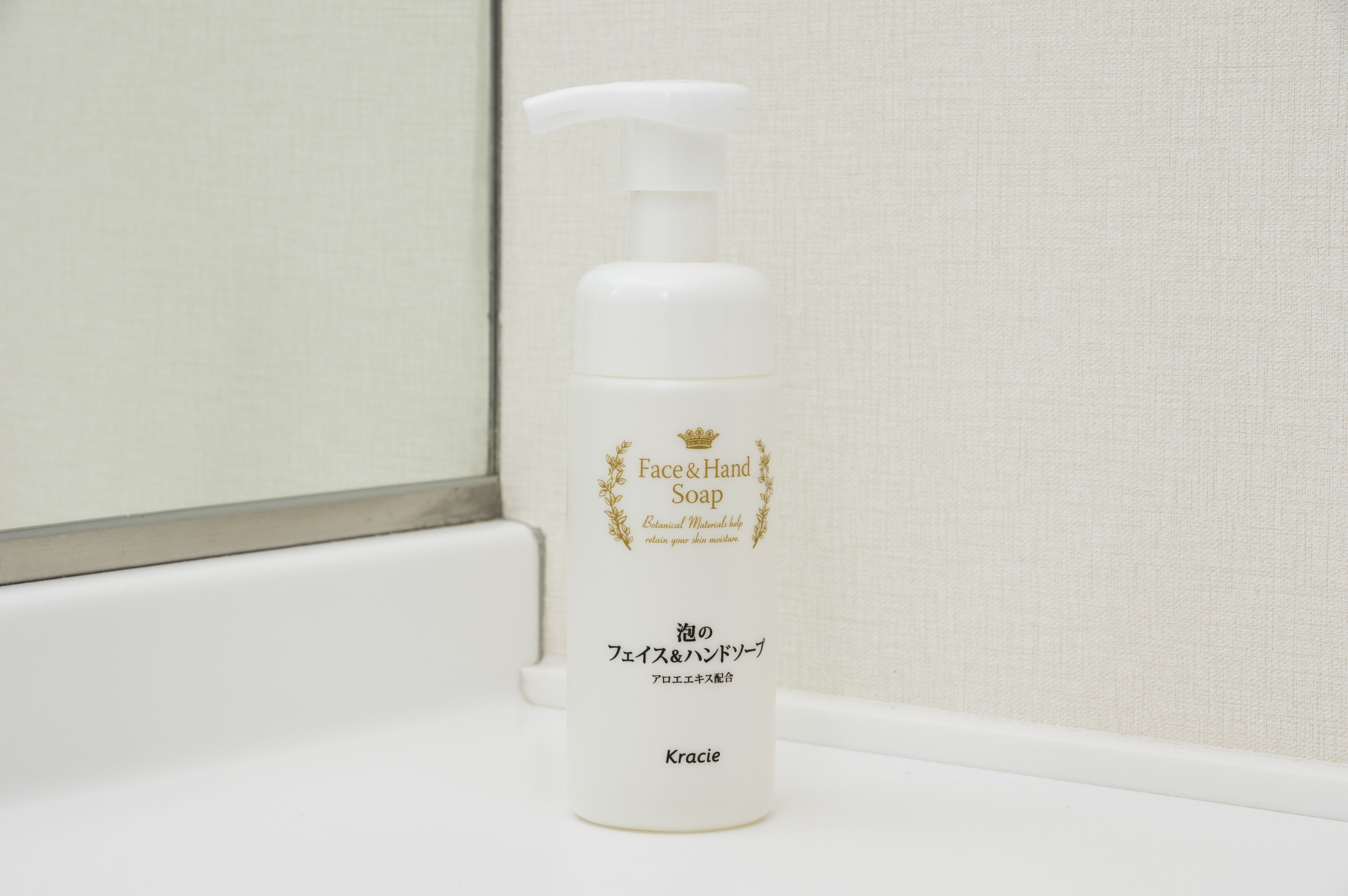 Una botella de jabón para manos y rostro sobre una encimera de baño.