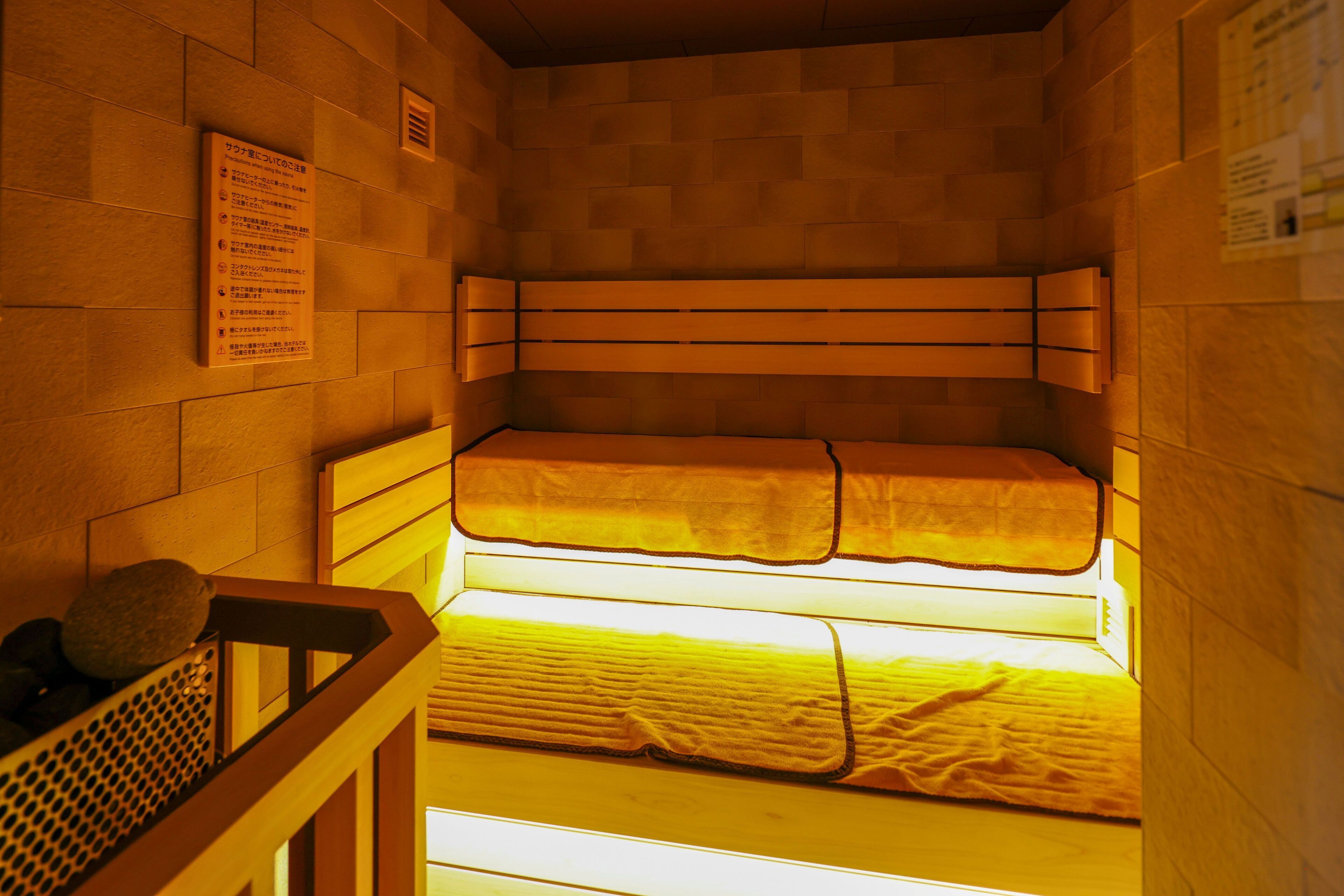 A small, enclosed room with two beds, a wooden bench, and a wall-mounted sign with text.