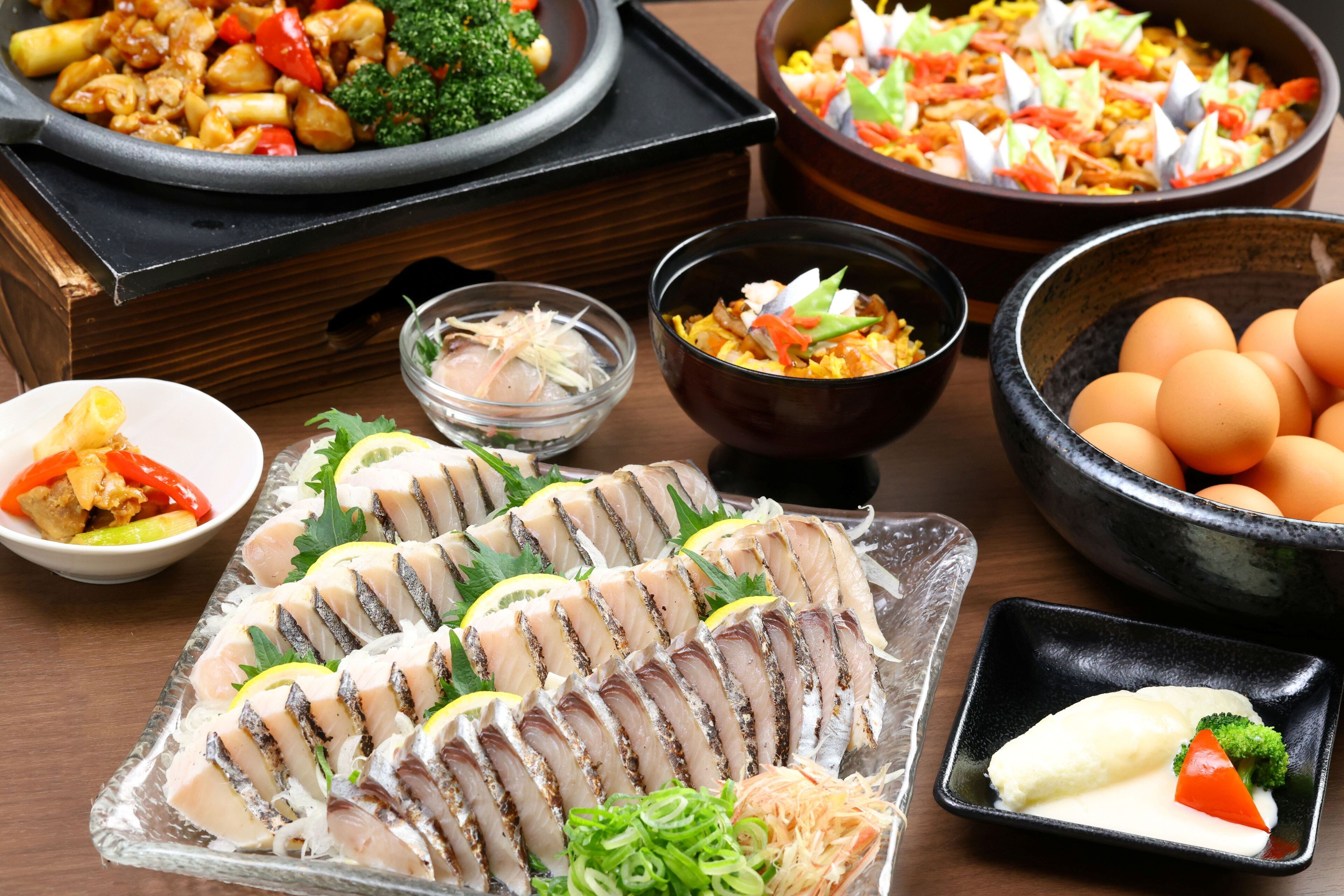 A variety of dishes including sashimi, vegetables, and eggs on a wooden table.
