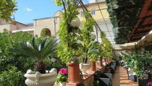 An outdoor café area with terracotta planters, wicker furniture, and a tiled floor. - Bed & Breakfast Medea (Naples)