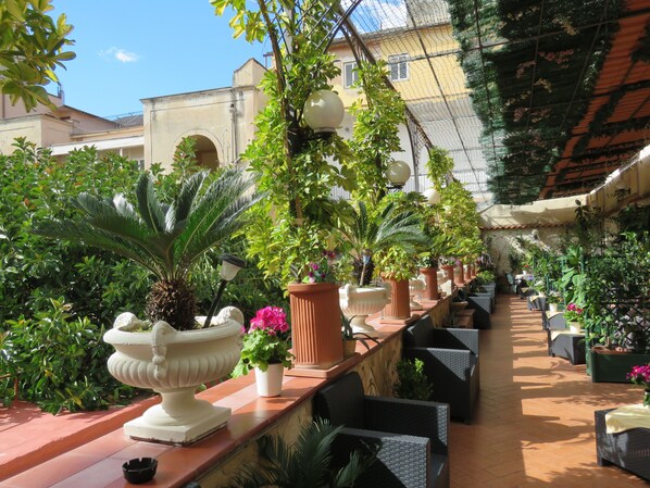 An outdoor café area with terracotta planters, wicker furniture, and a tiled floor. - Bed & Breakfast Medea (Naples)