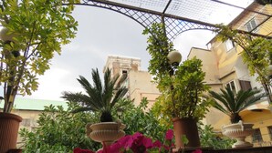 A courtyard with potted plants, a fountain, and a building in the background. - Bed & Breakfast Medea (Naples)