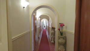 A hallway with a red carpet, white walls, and a wooden door on the right. - Bed & Breakfast Medea (Naples)