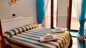 A hotel room with a bed, a nightstand, a window with curtains, and a view of the outside. - Bed & Breakfast Medea (Naples)