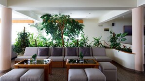 Eine moderne Lobby mit einer großen Couch, zwei Couchtischen und verschiedenen Zimmerpflanzen.