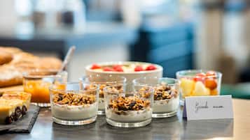 Un bufé de desayuno con diversos platillos, incluyendo parfait de yogur, fruta y pasteles.