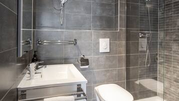 Une salle de bain moderne avec un lavabo blanc, des toilettes et une douche séparée par une paroi en verre.