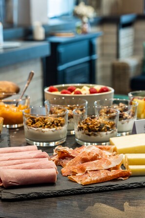 Een ontbijtbuffet met diverse soorten eten, zoals ham, kaas en fruit.