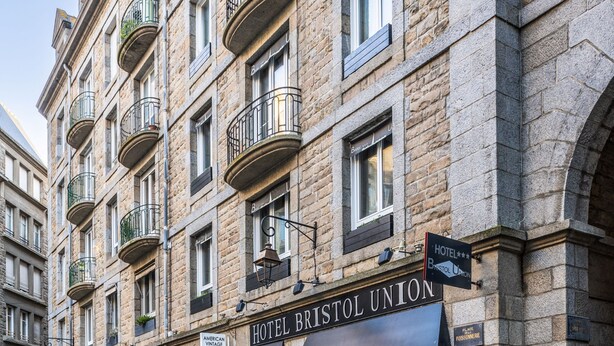 Un hotel de varios pisos con fachada de piedra, balcones y un cartel que dice 'HOTEL BRISTOL UNION'.