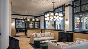 Un interior moderno con un sofá, una mesita de centro y una chimenea. Hay ventanas amplias y una vista de una tienda.
