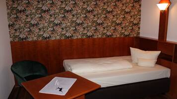 Habitación de hotel con cama, escritorio, silla y papel tapiz floral.