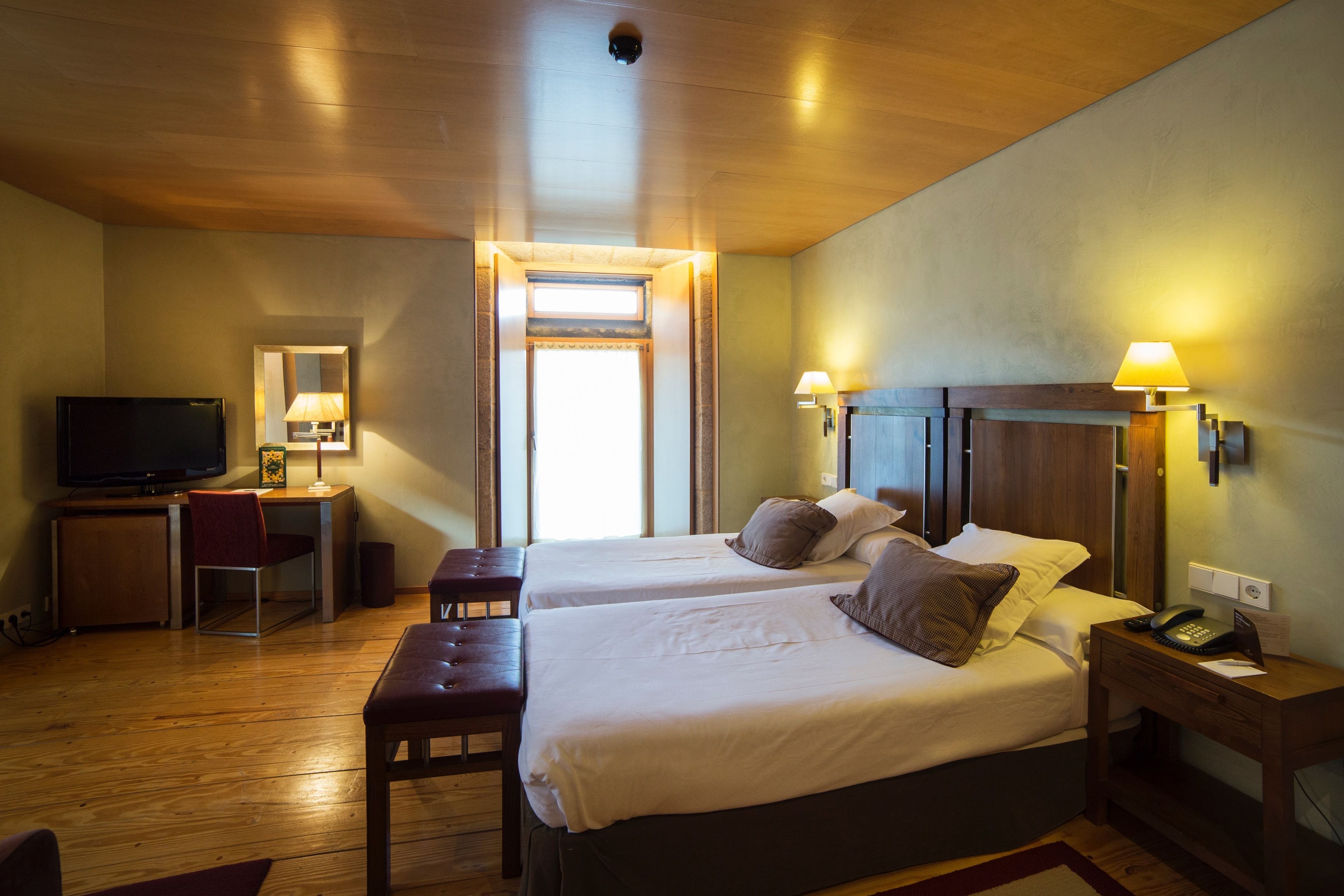 Une chambre d’hôtel avec deux lits, un bureau avec une télévision et un petit coin salon.