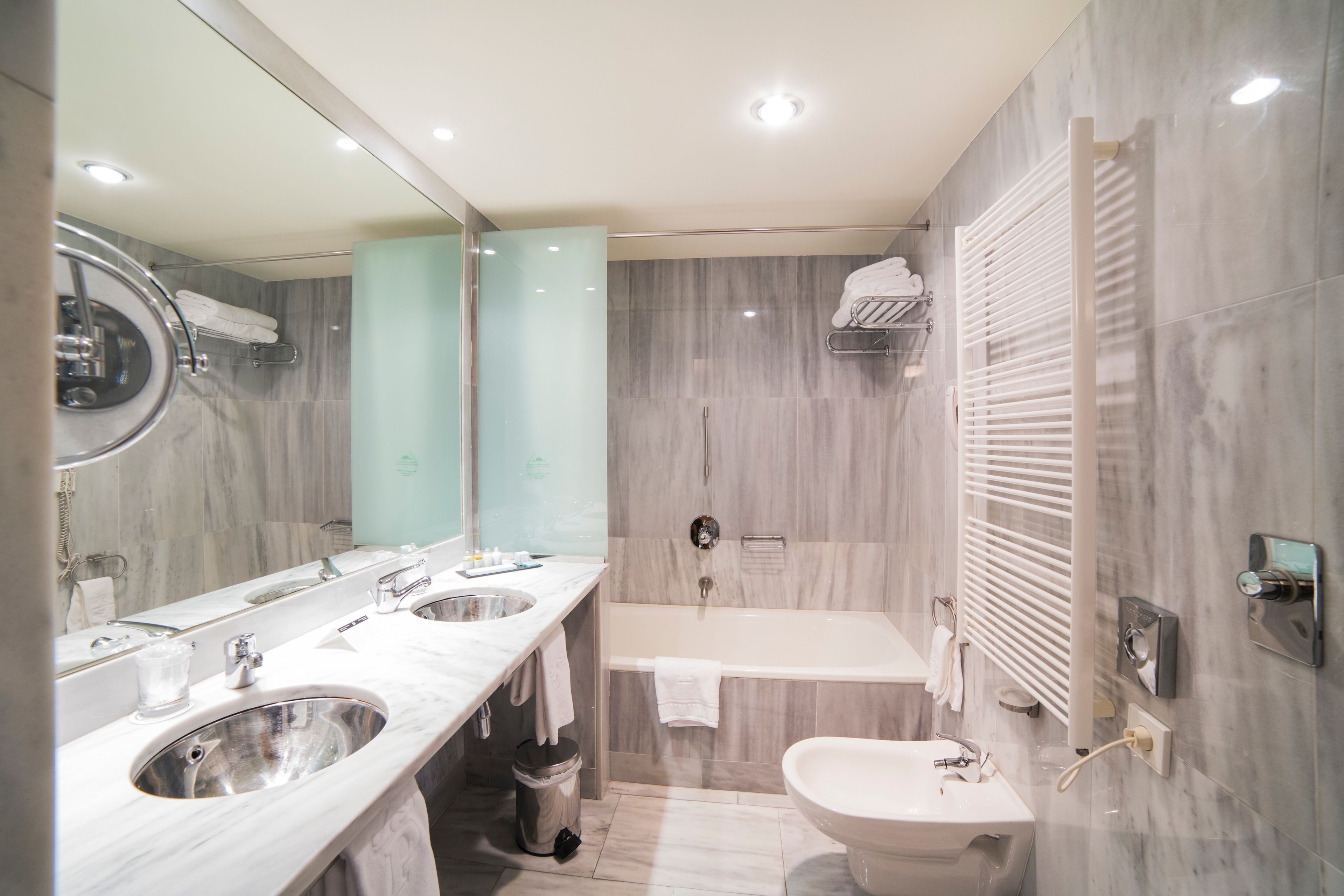 Un baño moderno con un espejo grande, dos lavamanos, una bañera y una ducha.