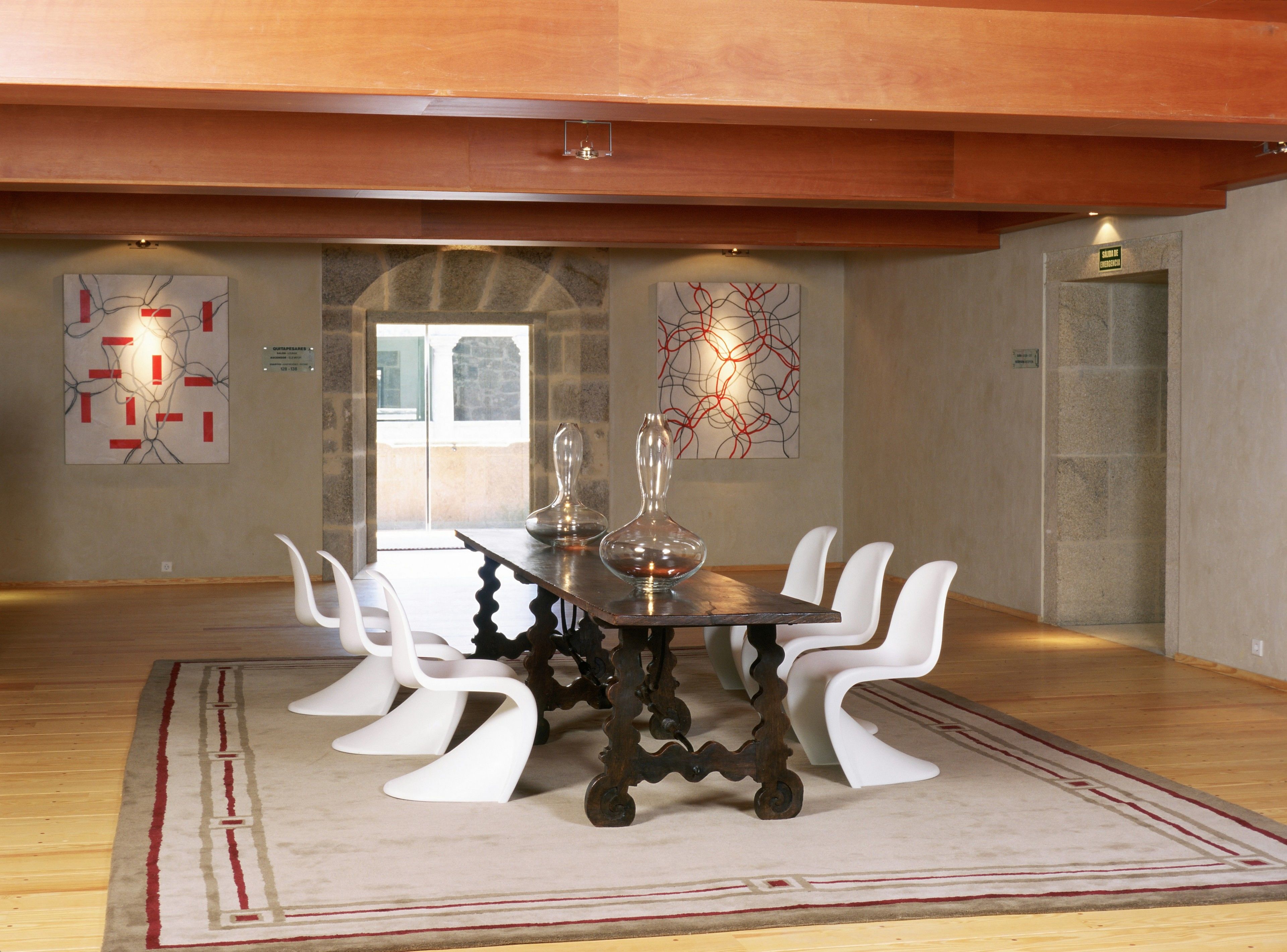 A dining area with a round table, white chairs, and abstract art on the walls.