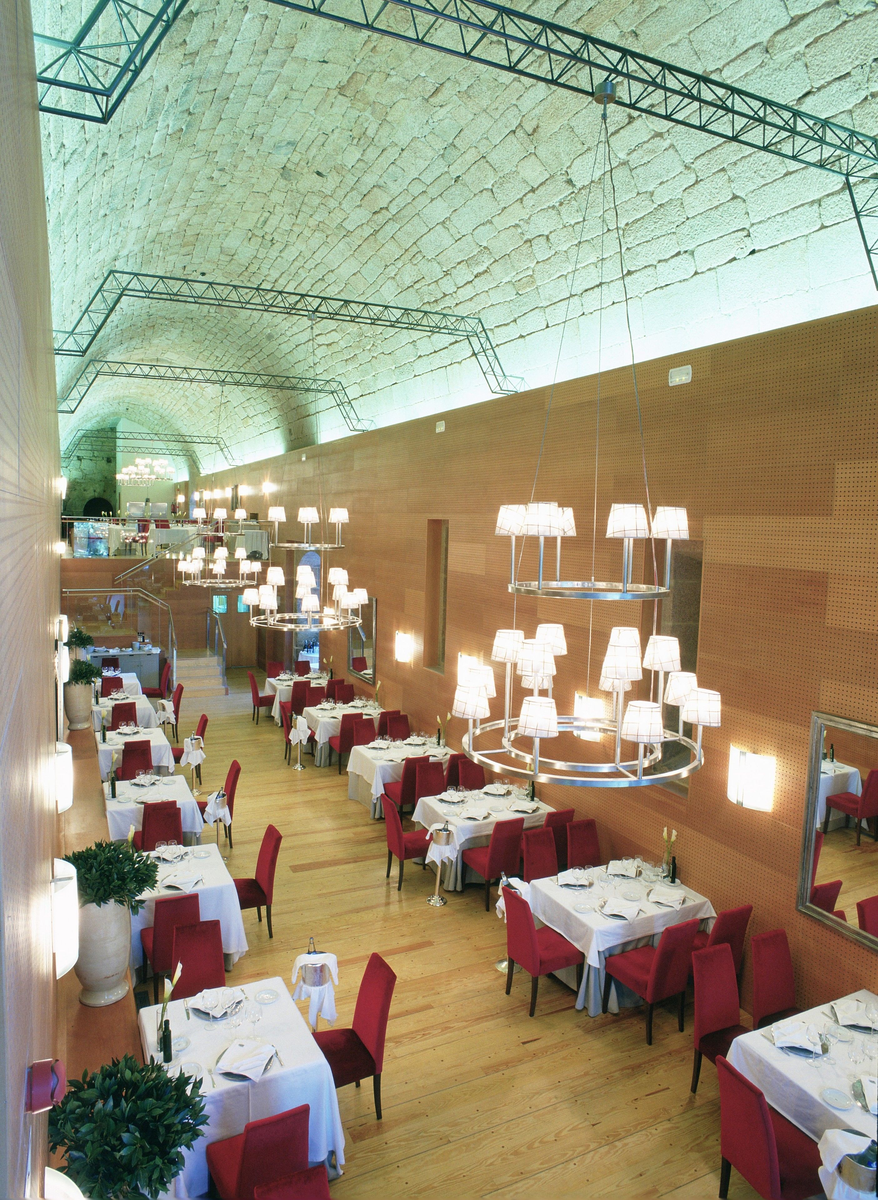 Un restaurant spacieux, doté de nombreuses tables et chaises, de hauts plafonds et d’un éclairage moderne.