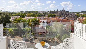 A balcony with a glass railing, white chairs, a small table, and a bowl. - Boutique Hotel Casa do Outeiro - Arts & Crafts (Batalha)
