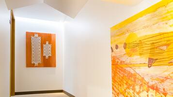 A staircase with a wooden handrail and carpeted steps, leading to a room with a large abstract painting on the wall.