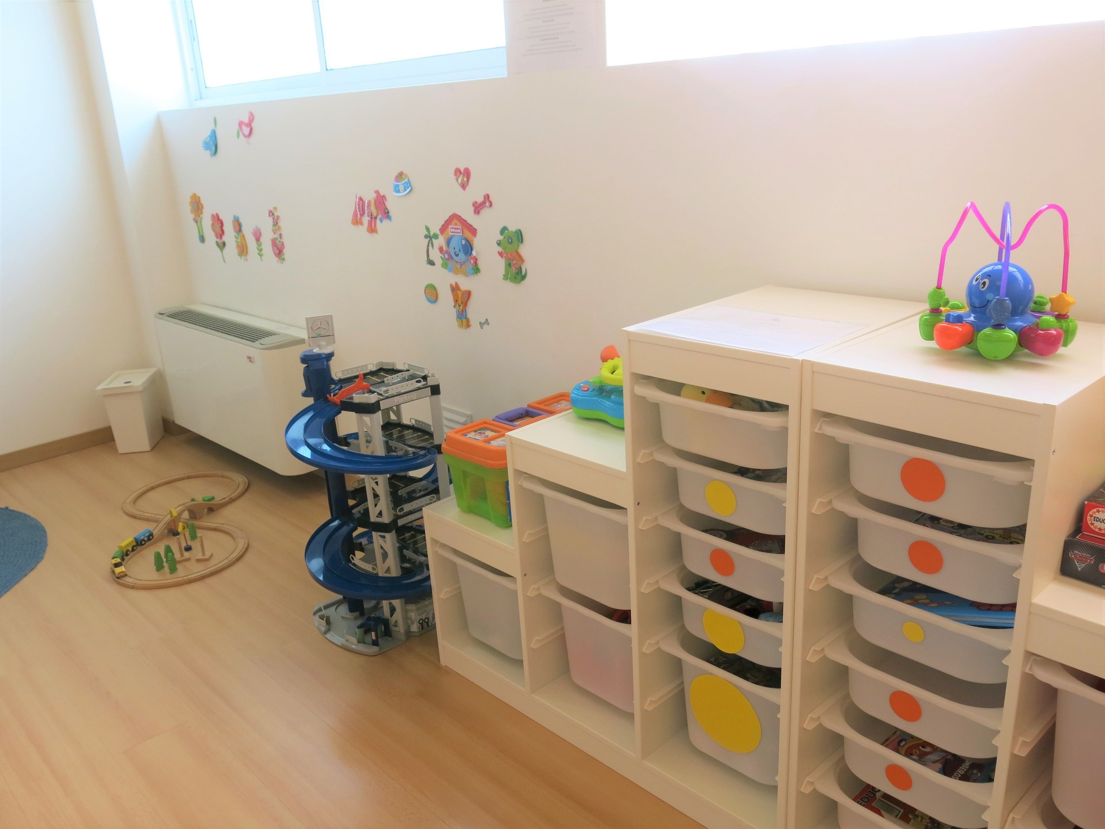 Un área de juegos infantil con una estructura azul y blanca, cajones de almacenamiento y adornos en la pared.
