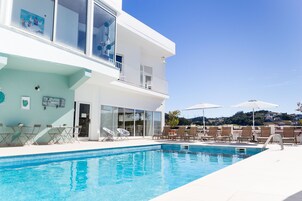 Una piscina techada, una piscina al aire libre de temporada, sombrillas